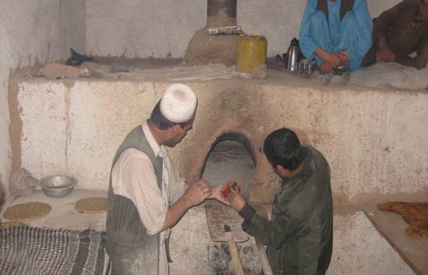 An overview of a community bakery from inside. The bakeries and his assistant are showing the Dash/oven using a torch.