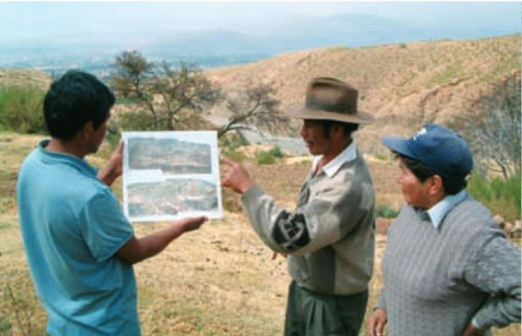 Individual planning (at farmer level) of activities to treat the large gully in the background: a PROMIC engineer and local people are involved. Note the city of Cochabamba in the distance. 
