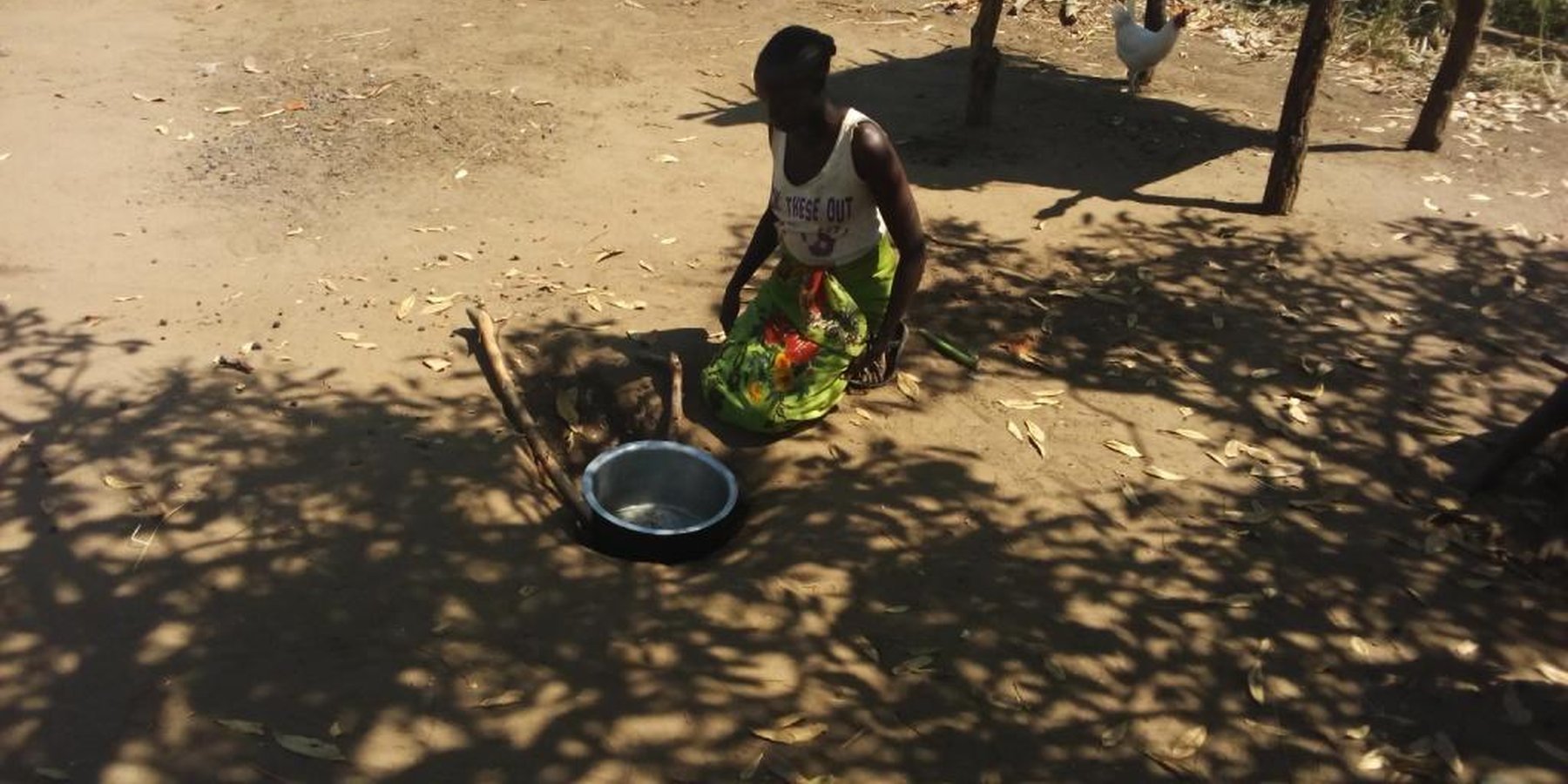 Wife of Odoch George preparing to boil water using ground stove.
